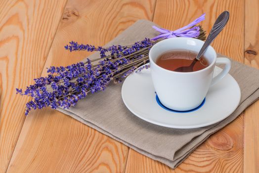 tea in a white cup and a bunch of dried lavender on a linen napkin close-up