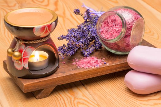 lavender soap and lavender sea salt on a wooden stand with a burning candle