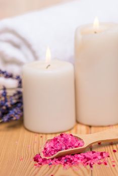 close up sea salt in wooden spoon and burning candles soothing spa treatments with lavender