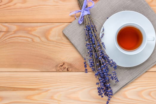 top view cup of soothing tea with lavender and a bunch of flowers on a linen napkin on wooden boards