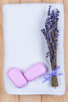a bunch of dried lavender on a white terry towel and two bars of soap for the spa objects top view