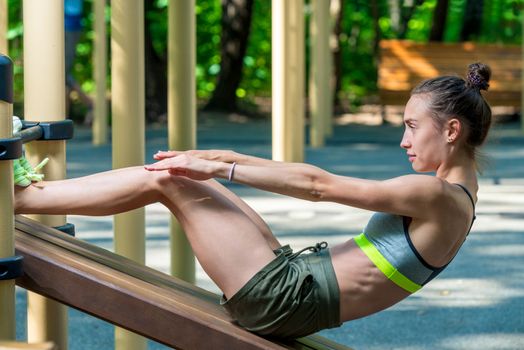 muscular athlete shakes the press on the playground in the park on a summer morning