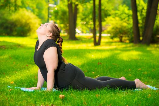 work on yourself - a sports woman plus size in the park performs stretching exercises