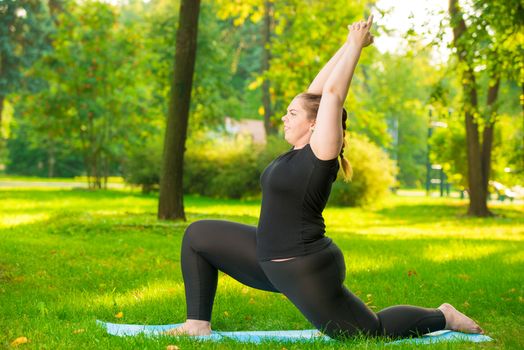 girl in the park is engaged in his figure, yoga exercises in the fresh air, model plus size