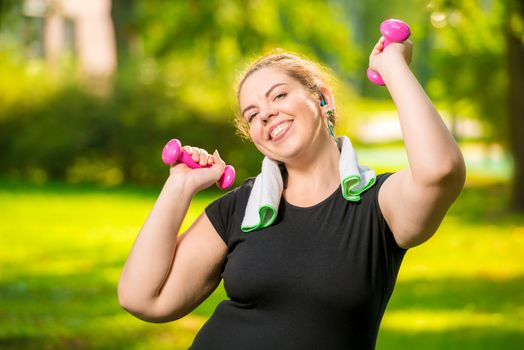 happy young plus size model with dumbbells in the park during workout