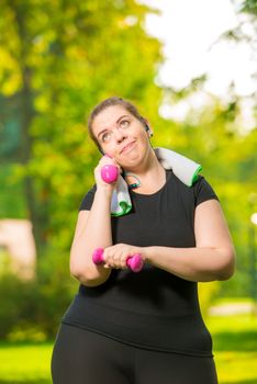 smiling plus-size models doing exercises with dumbbells during a summer park workout