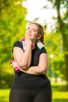 dreaming about slim body model plus size is engaged with dumbbells during a workout in a summer park