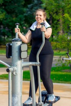portrait of an active fat woman without complexes is engaged on a stepper simulator in the park