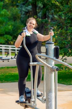 portrait of a young active fat woman engaged on a stepper simulator in a park