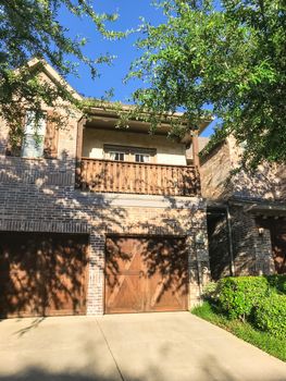Brand new attached houses townhome style with double wooden garage doors, small front yard. Townhouse units in suburban Dallas, Texas, USA. Front view facade of two stories house nice trim landscape