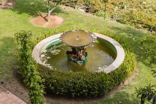 View of an old oval fountain surrounded by boxwood in the garden of Granja de Palma de Mallorca
