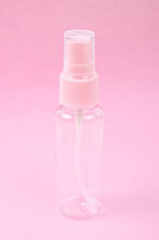 Clear pink plastic bottle spray on pink background.