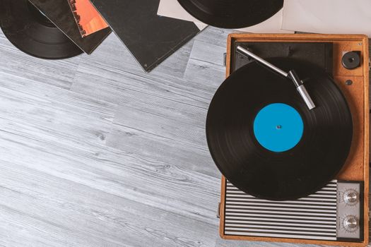 Vintage Gramophone with a vinyl record on gray wooden table, top view and copy space.