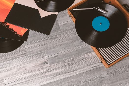 Vintage Gramophone with a vinyl record on gray wooden table, top view and copy space.