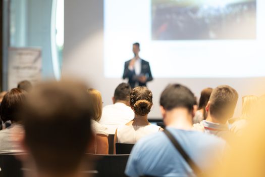 Male speaker giving a talk in conference hall at business event. Audience at the conference hall. Business and Entrepreneurship concept. Focus on unrecognizable people in audience.