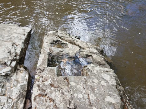 large grey stone or boulder in river or stream water