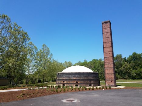 curved brick building with with tall brick chimney and grasses