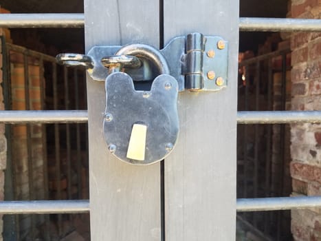 silver metal lock securing a closed metal door with red bricks