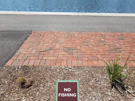 no fishing sign with red bricks and asphalt and water