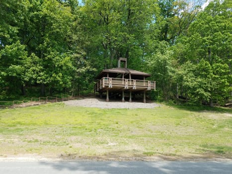 brown wooden picnic pavilion on hill with green grass and trees or forest