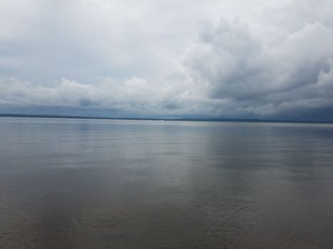 calm water in river or lake and white clouds and hills