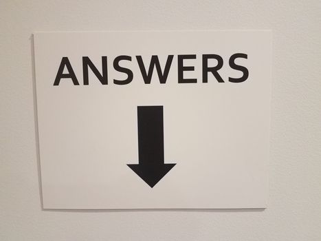 white paper answers sign with black down arrow or pointer on wall