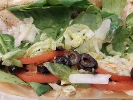 sandwich bread with olives and tomato, spinach, and lettuce