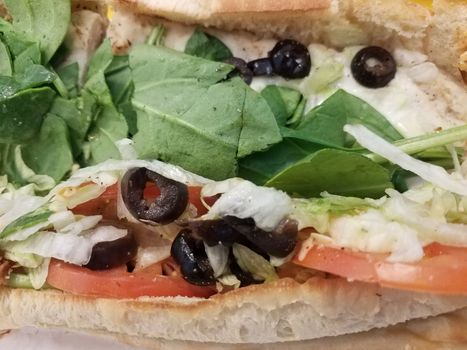 sandwich bread with olives and tomato, spinach, and lettuce