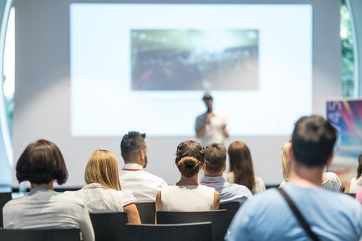 Speaker giving a talk in conference hall at business event. Audience at the conference hall. Business and Entrepreneurship concept. Focus on unrecognizable people in audience.