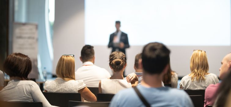 Male speaker giving a talk in conference hall at business event. Audience at the conference hall. Business and Entrepreneurship concept. Focus on unrecognizable people in audience.