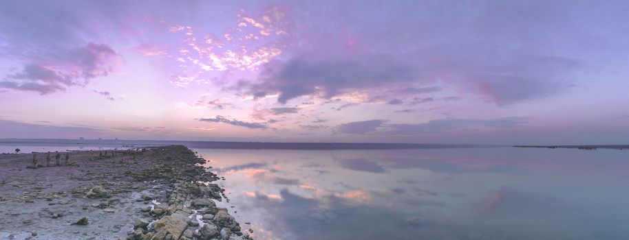 Panoramic view of the clouds above the water in a pink and purple sunset