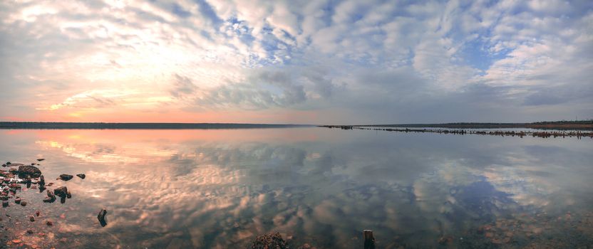 Sunset clouds reflected on the water surface on a warm summer evening