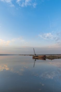 Panoramic view of the lake and the old boat at sunset of a summer day