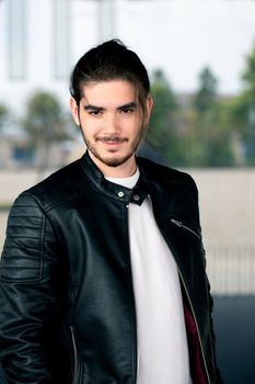 Half length portrait of handsome bearded man dressed in fashionable clothes standing on street against while wall background with area for advertising content.Handsome hipster guy posing on copy space