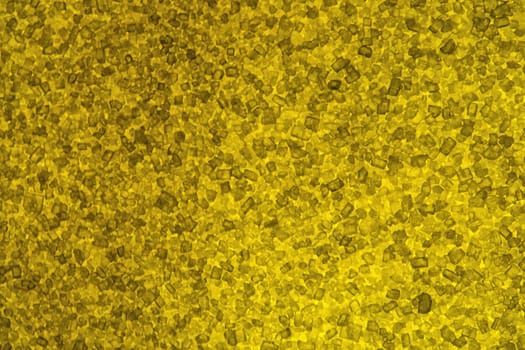 Macro view (5x) of granulated sugar that is lit from behind with a yellow-filtered light.