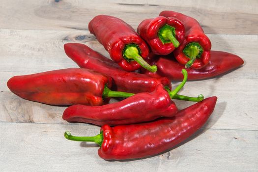 Sweet long pepper lies in a heap against a light, wooden floor