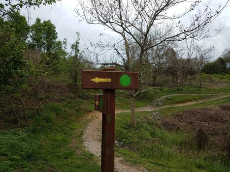 sign with green dots and yellow arrows and trail or path