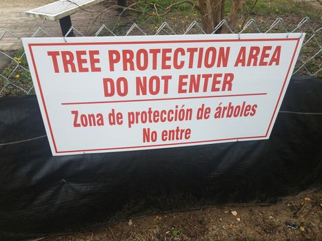 tree protection area do not enter sign with spanish on metal fence