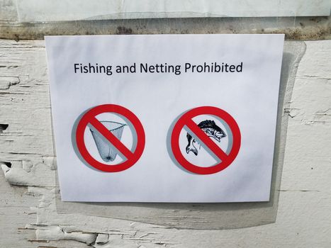 fishing and netting prohibited sign on paper and wood wall