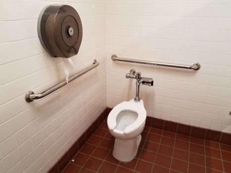 red and white tiles with toilet and toilet paper dispenser in bathroom or restroom