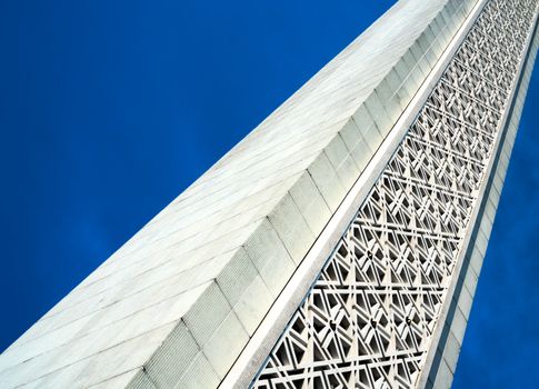 tilted modern white minaret with star patterns decoration with a blue sky background