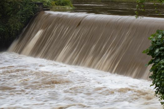 Brown rain runoff from Hurricane Florence rushes over the spillway on the Readdies River in North Wilkesboro, NC.