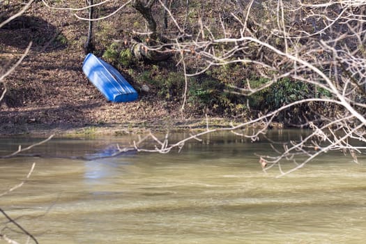 Small blue metal boat rests upside down on the western bank of the Yadkin River in Wilkes Couny, North Carolina.