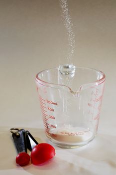 Stop motion shot of cane sugar being poured into measuring cup.
