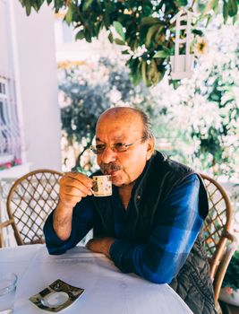 Old man enjoys his cup of coffee outside on spring day.