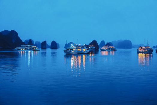 Ha Long bay at night with cruise ship lamps and limestone rocks reflections