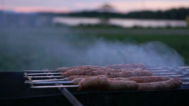 Grilling sausages at sunset outdoors gathering with friends and family. Sunner time