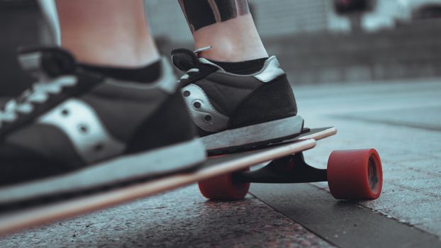 Woman skateboarder legs skateboarding at grey city