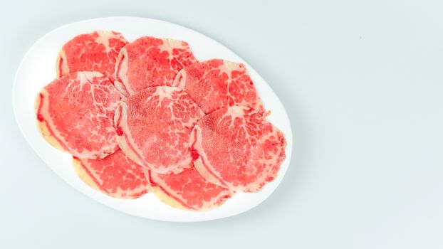 Top view of some raw beef on a plate over white background