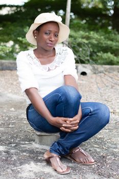 young woman sitting on a piece of brick in height on a slab.